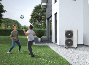 Two boy in garden playing football near house with air source heat pumps